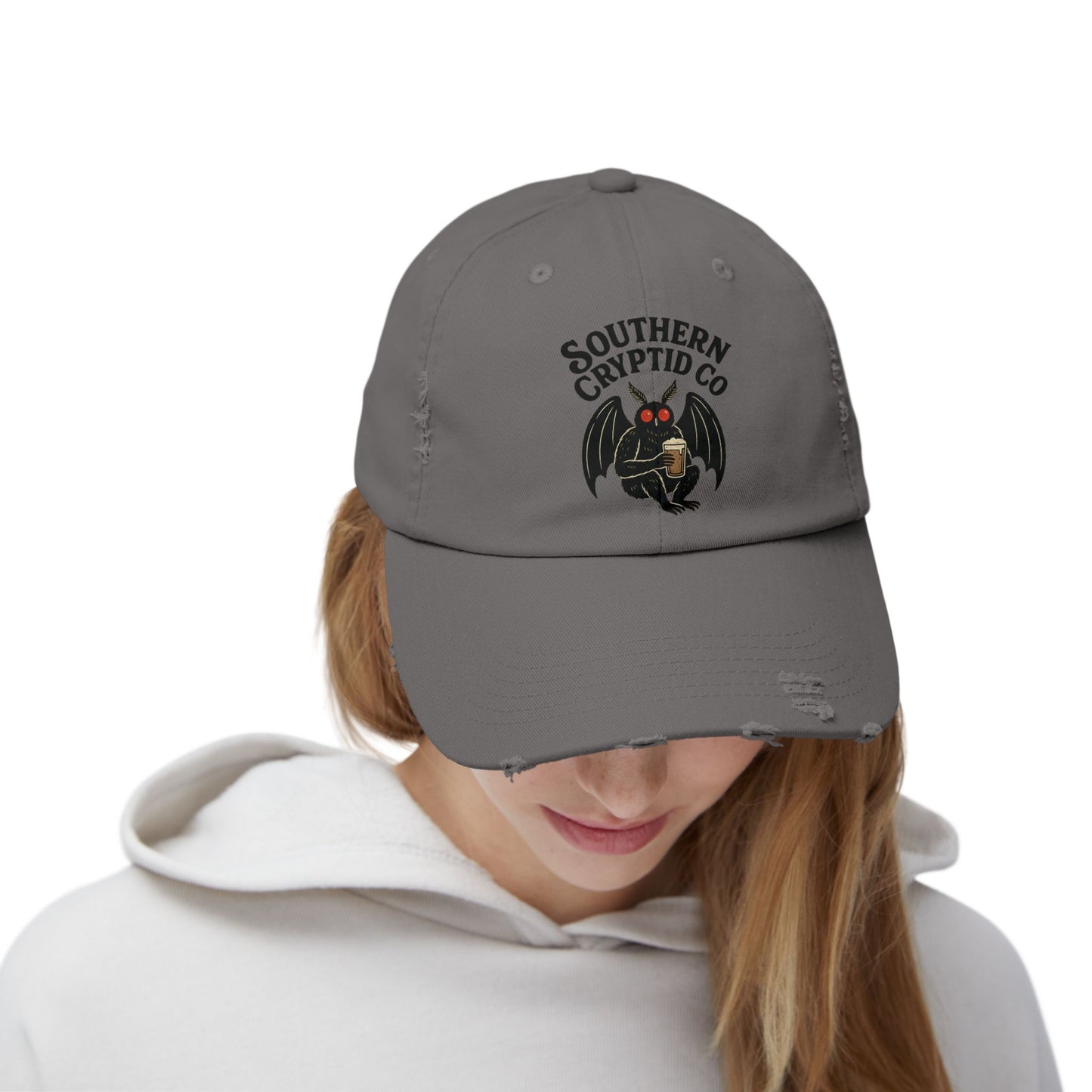 Distressed dad hat with Southern Cryptid Co. logo featuring Mothman holding a pint of beer.